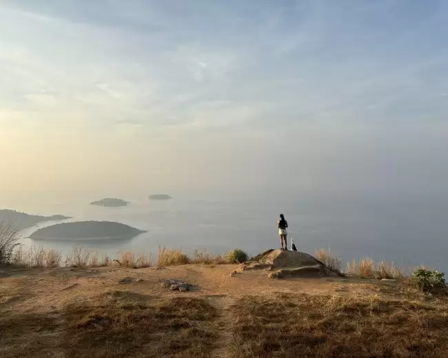 Romantic couple walking hand-in-hand along Nai Harn Beach at sunset in Phuket