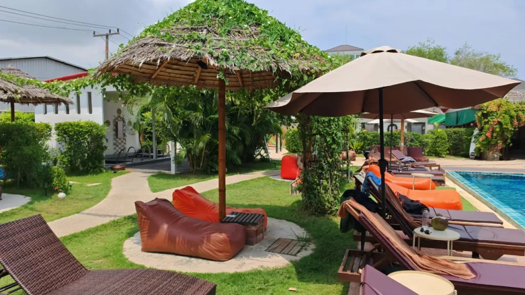Outdoor relaxation area at AllThai Spa in Chalong, Phuket, featuring sun loungers, beanbags, and tropical garden by the pool