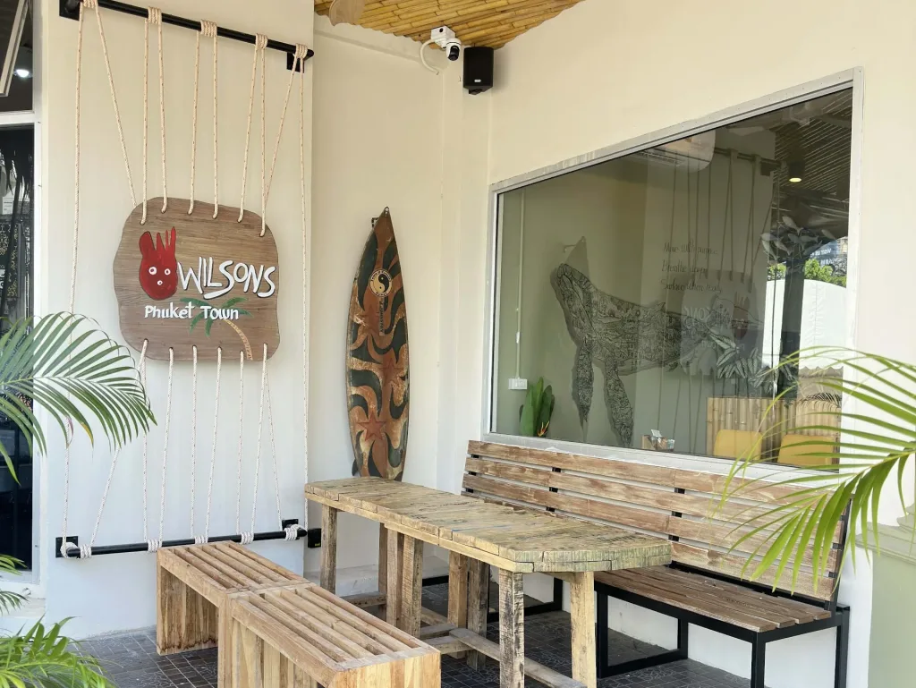 Outdoor seating area at Wilson’s Cafe Phuket Town with wooden benches and bamboo ceiling